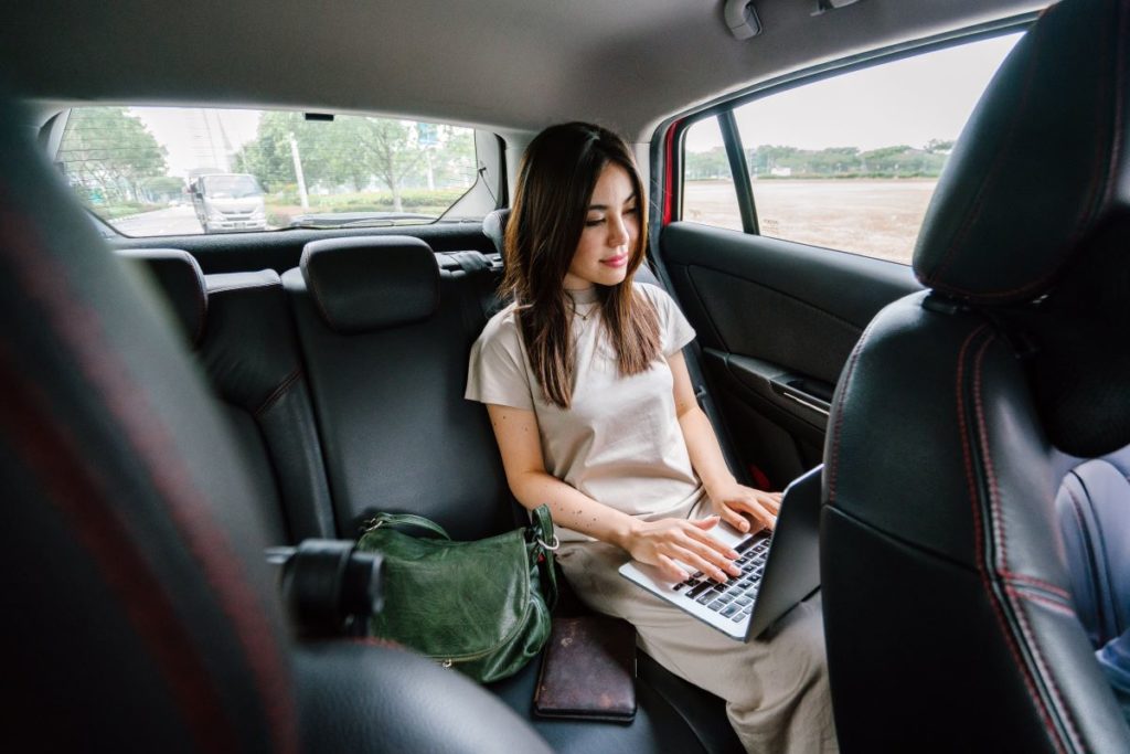 woman working on laptop while inside a car
