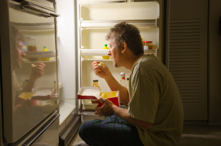 man eating near a refrigerator