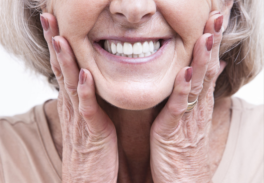 senior woman smiling while holding her cheeks