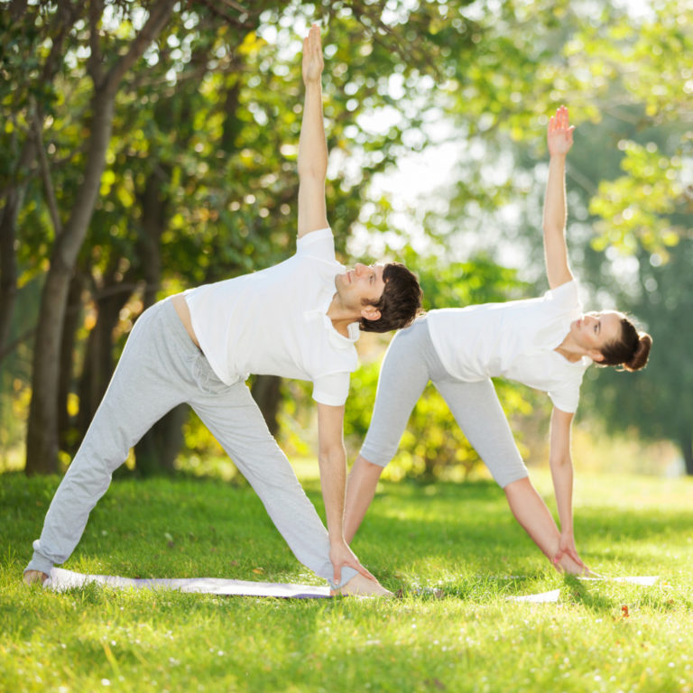 couple stretching in a clearing near the woods