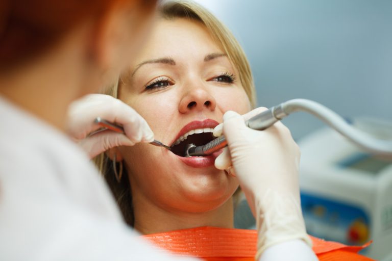 woman getting dental cleaning or procedure at dentist