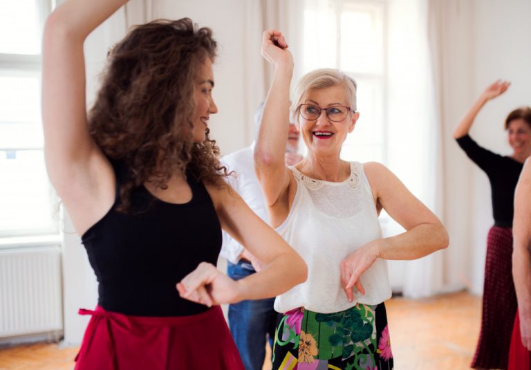Two women smile while dancing in a ballroom dance class