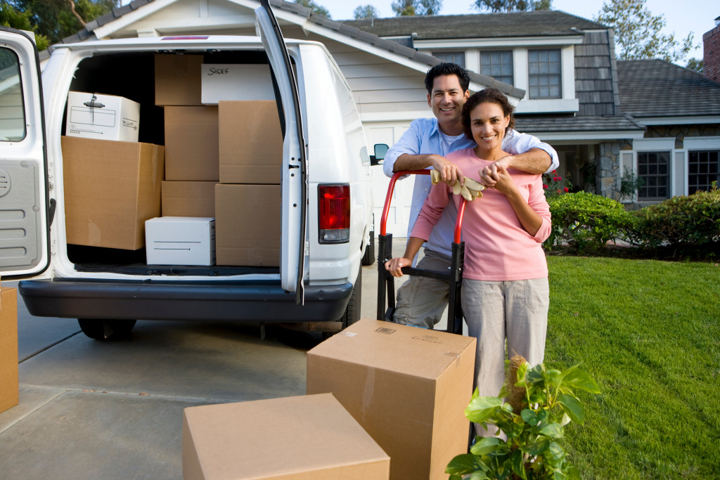 man and woman embracing with moving boxes and van in the side